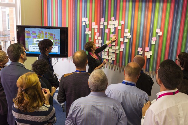 GDS team in a meeting with a speaker placing lots of post-its on a wall.