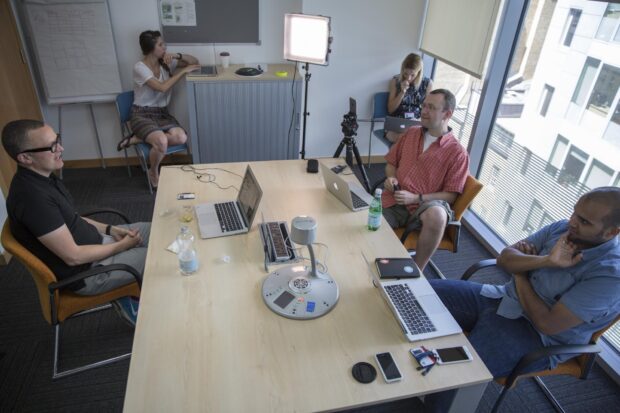 Five GDS colleagues sitting on chairs with laptops, getting ready for the Periscope session