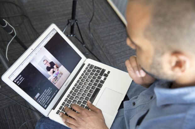 Person sitting with laptop screen displaying a Periscope feed.