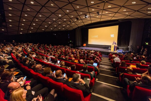 Image taken at Sprint 16 showing a stage with a full audience looking at the speaker